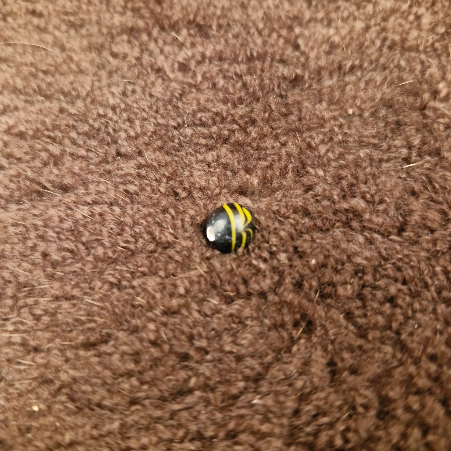 Black spherical glass bead with yellow thread pattern