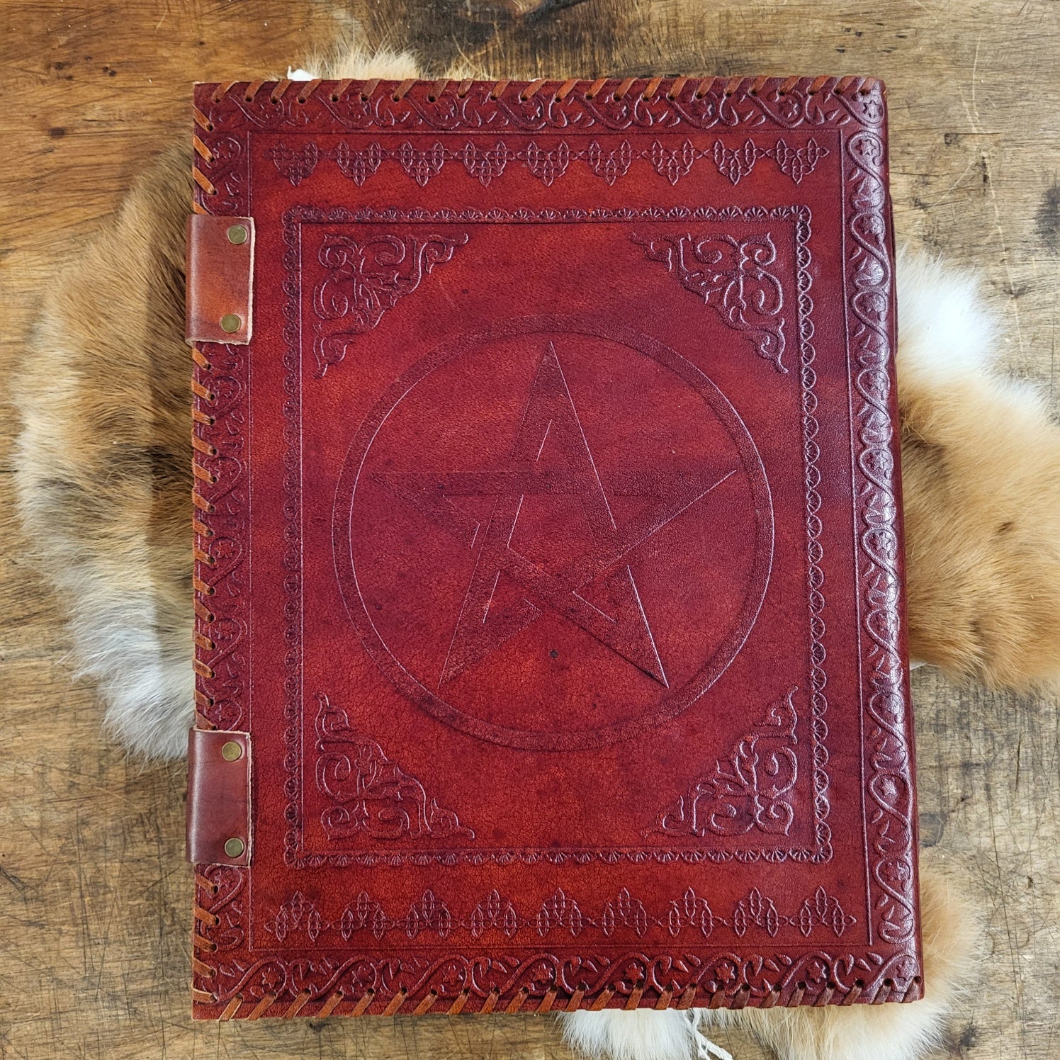 Riesiges Lederbuch mit geprägtem Pentagramm und sechs Steinen