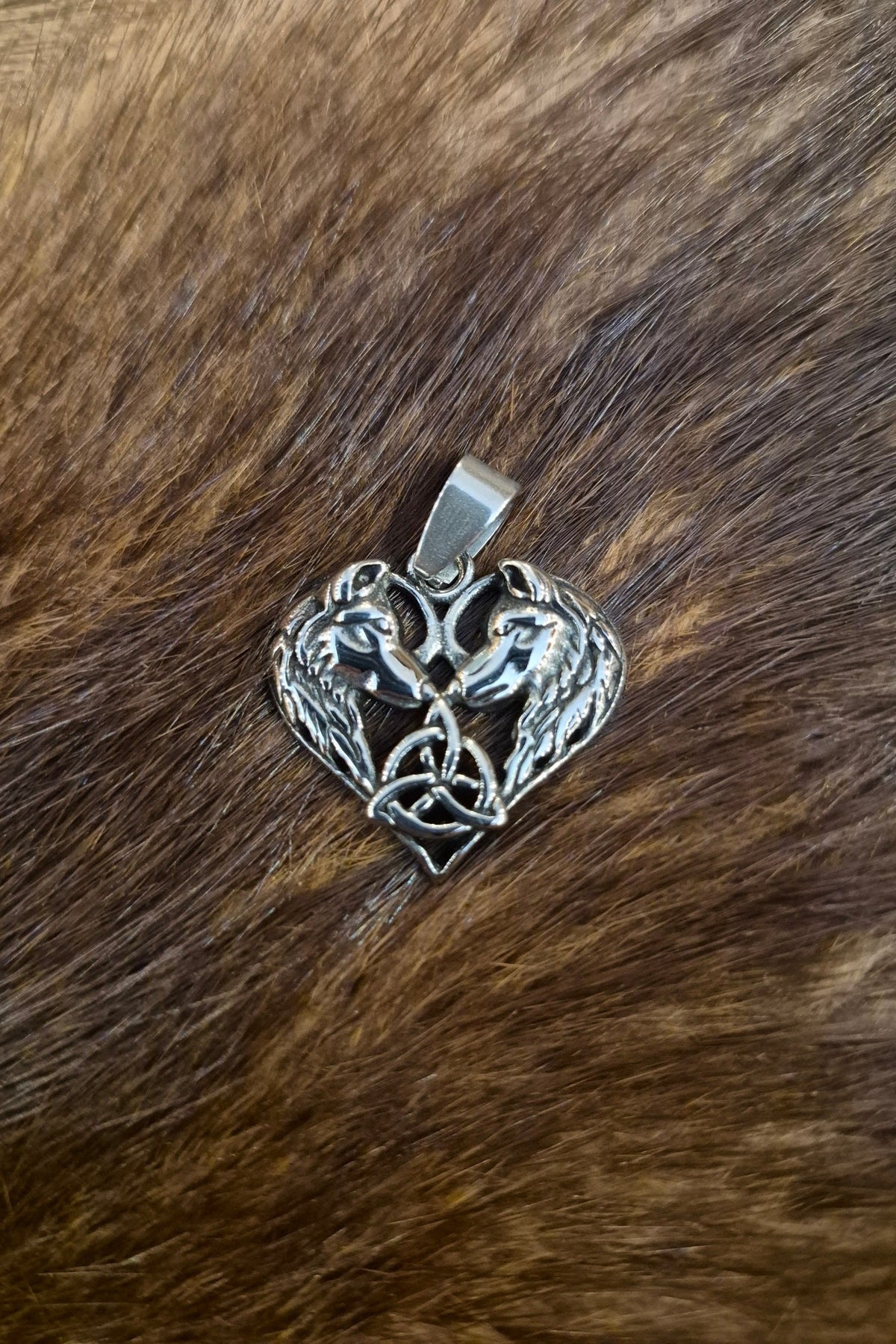 Ein Wicca Amulett in Herzform welches zwei Wölfe zeigt die sich anschauen aus Edelstahl.