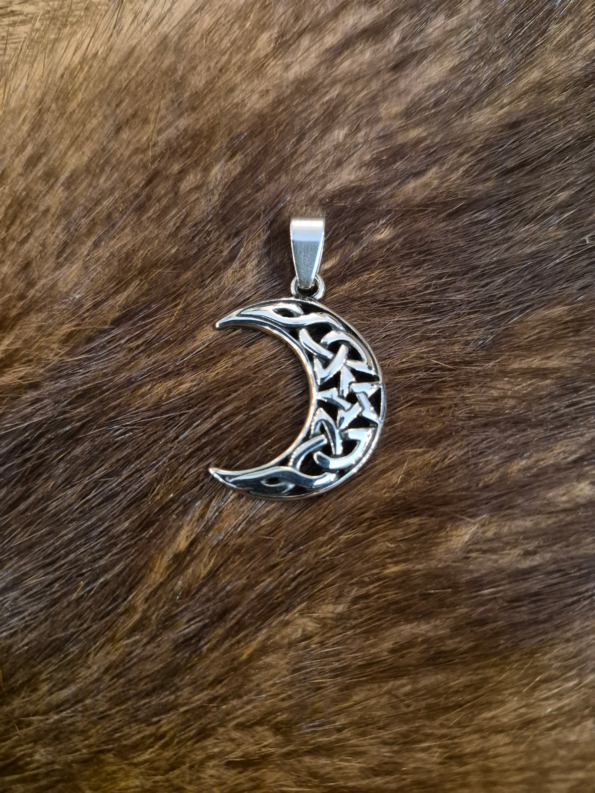 Ein Wicca Amulett das einen Halbmond mit keltischen Verzierungen zeigt und  aus Edelstahl gefertigt wurde.