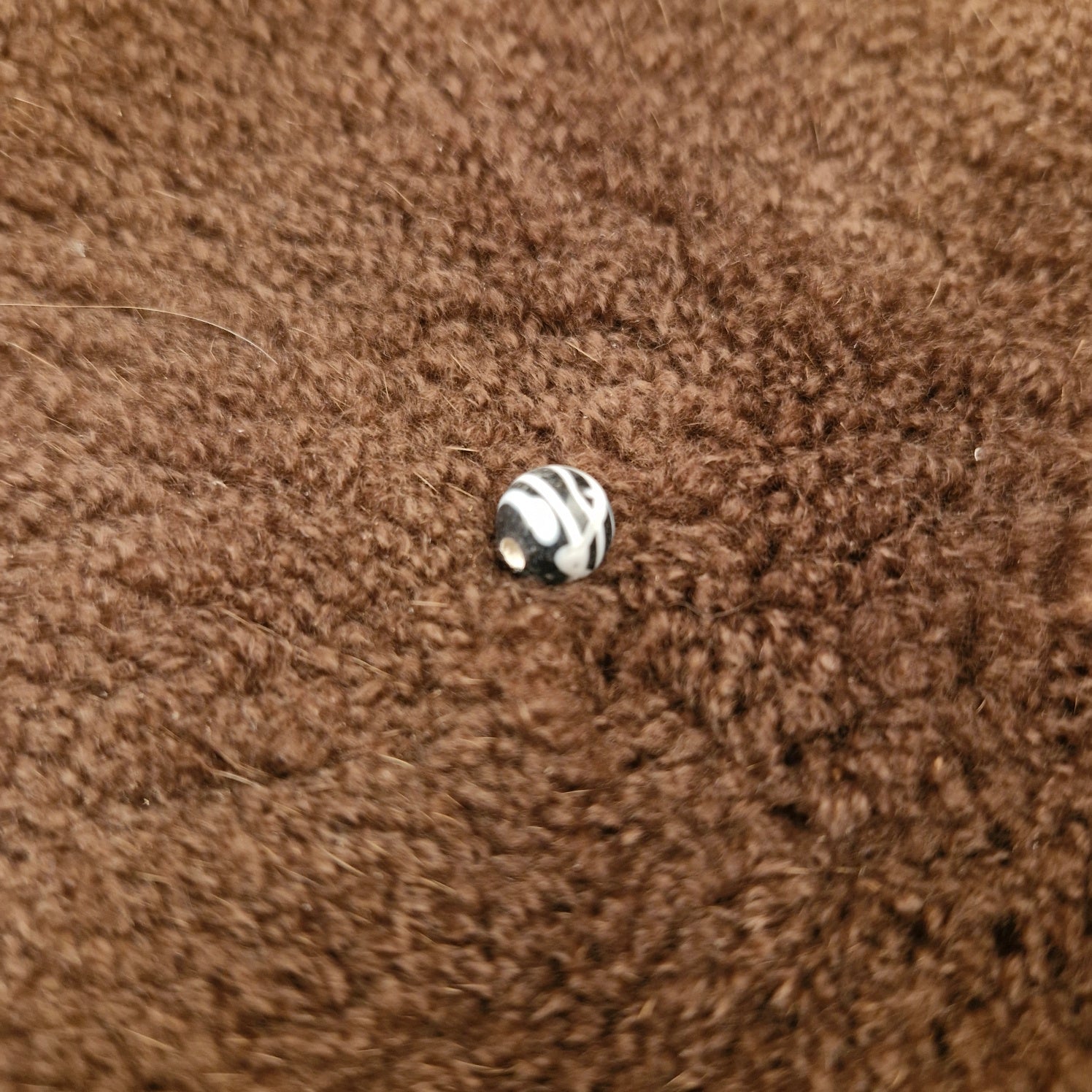 Black spherical bead with white thread pattern made of glass